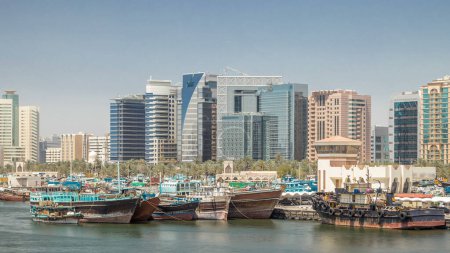 Photo for Trading wooden boats in the port timelapse. Merchant ships on the Creek Canal. Skyscrapers on background. View form bridge in Deira - Royalty Free Image