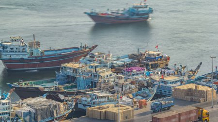 Photo for Loading a ship in Port Said timelapse in Dubai, Deira creek, UAE. Aerial top view from above with many old boats at sunset with warm light - Royalty Free Image