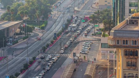 Téléchargez les photos : Dubai Creek zone entourée de bâtiments modernes et la circulation achalandée sur une rue avec parc timelapse. Vue aérienne de dessus au coucher du soleil avec de longues ombres et une lumière orange - en image libre de droit