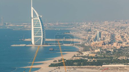 Téléchargez les photos : Vue Aérienne de Jumeirah Beach et Dubai skyline avec Burj Al Arab au timelapse du soir, Émirats Arabes Unis. Bateaux et circulation sur la route - en image libre de droit