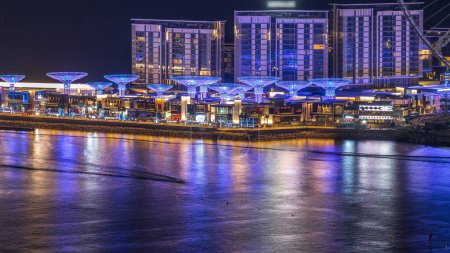 Téléchargez les photos : Bluewaters île timelapse de nuit aérienne avec roue ferris, nouvelle zone de marche avec centre commercial et restaurants, lieu de loisirs et de voyage nouvellement ouvert à Dubaï - en image libre de droit