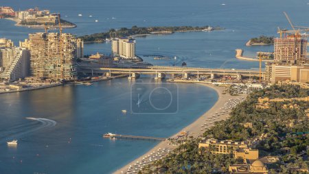 Téléchargez les photos : Vue aérienne du pont vers Palm Jumeirah Island timelapse. Vue panoramique en soirée avec villas, hôtels et yachts. Certains bâtiments sont en construction - en image libre de droit