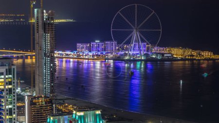 Téléchargez les photos : Bluewaters île timelapse de nuit aérienne avec roue ferris, nouvelle zone de marche avec centre commercial et restaurants, lieu de loisirs et de voyage nouvellement ouvert à Dubaï - en image libre de droit