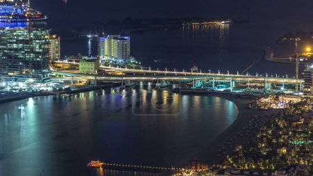 Téléchargez les photos : Vue aérienne du pont vers Palm Jumeirah Island timelapse de nuit. Vue de dessus avec villas éclairées, hôtels et yachts. Certains bâtiments sont en construction - en image libre de droit
