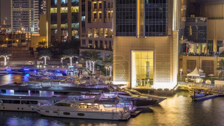 Téléchargez les photos : Vue aérienne de Dubai Marina avec centre commercial, restaurants, tours et yachts nuit timelapse, Émirats arabes unis. Vue de dessus du canal avec bâtiments éclairés et front de mer - en image libre de droit