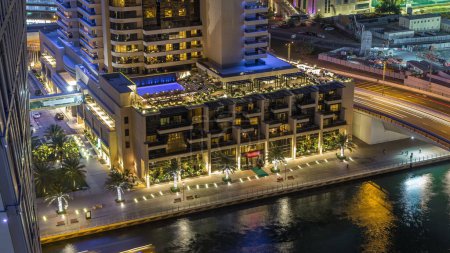 Foto de Canal de lujo Dubai Marina con tráfico y paseo marítimo con restaurantes de noche timelapse, vista superior desde arriba con rascacielos iluminados. Dubai, Emiratos Árabes Unidos - Imagen libre de derechos