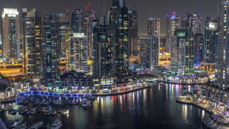 Foto de Canal de lujo Dubai Marina con barcos que pasan y paseo marítimo con restaurantes timelapse noche, vista superior desde arriba con rascacielos iluminados. Dubai, Emiratos Árabes Unidos - Imagen libre de derechos