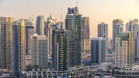 Téléchargez les photos : Belle vue aérienne sur la promenade et le canal de Dubai Marina avec des yachts flottants et des bateaux avant le coucher du soleil à Dubaï, Émirats arabes unis. Tours et gratte-ciel modernes le soir - en image libre de droit