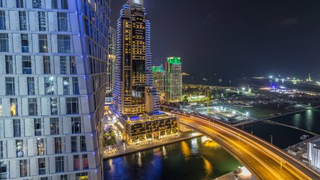 Téléchargez les photos : JBR et Dubai Marina timelapse de nuit aérienne. Tours et gratte-ciel modernes éclairés, circulation sur le pont, yachts et bateaux flottant sur le canal - en image libre de droit