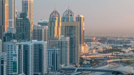 Photo for Dubai Marina skyscrapers aerial top view during sunrise at morning from JLT in Dubai timelapse, UAE. Modern towers with long shadows moving down and traffic on sheikh zayed road. - Royalty Free Image