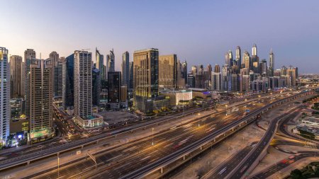 Photo for Dubai marina with traffic on sheikh zayed road panorama day to night transition timelapse lights turn on. The night illumination of skyscrapers, UAE. Aerial view from JLT - Royalty Free Image