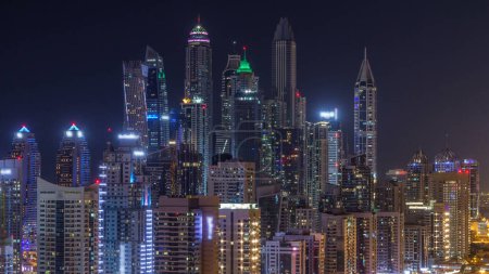 Foto de Fantástico horizonte en la azotea del puerto deportivo de Dubai timelapse durante toda la noche. Rascacielos iluminados de una gran ciudad que se apaga, Emiratos Árabes Unidos. Vista aérea desde JLT - Imagen libre de derechos