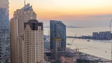 Téléchargez les photos : JBR et la marina de Dubaï après le coucher du soleil aérien du jour à la nuit transition timelapse. Tours et gratte-ciel modernes, yachts et bateaux flottant sur le golfe - en image libre de droit