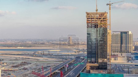 Photo for Construction activity in Dubai downtown with cranes and workers timelapse, UAE. Building of new skyscrapers and towers near crossroad junction - Royalty Free Image