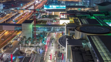 Téléchargez les photos : Vue aérienne de l'entrée du centre commercial avec centre financier route nuit circulation timelapse et passerelle du centre-ville de Dubaï - en image libre de droit