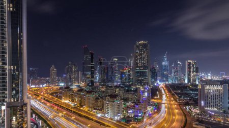 Aerial view to downtown and financial district in Dubai during all night timelapse, lights switching off. United Arab Emirates with illuminated skyscrapers and highways.