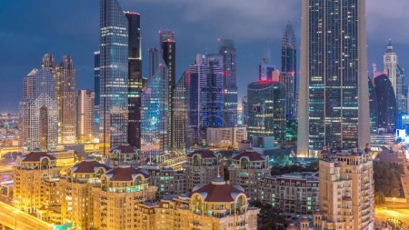 Téléchargez les photos : Vue panoramique des bâtiments de Sheikh Zayed Road et DIFC nuit à jour timelapse transition à Dubaï, EAU. gratte-ciel lumineux dans le centre financier vue aérienne d'en haut au centre-ville - en image libre de droit