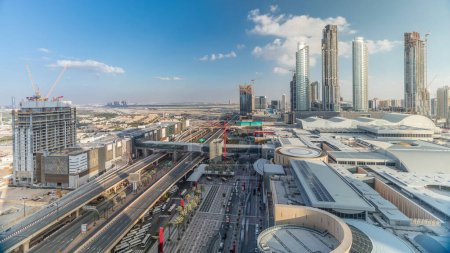 Téléchargez les photos : Vue aérienne du centre financier route timelapse avec centre commercial et bâtiment en construction avec grues du centre-ville, Dubai Creek port sur fond - en image libre de droit