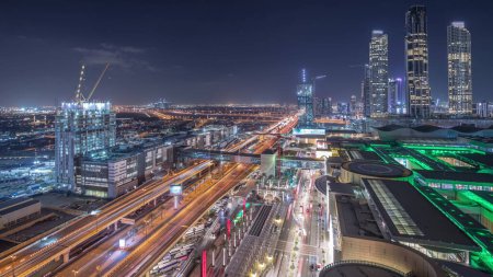 Téléchargez les photos : Vue aérienne du centre financier route nuit timelapse avec centre commercial et bâtiment en construction avec grues du centre-ville, Dubai Creek port en arrière-plan - en image libre de droit
