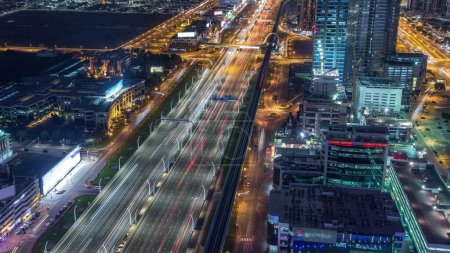 Photo for Aerial view to traffic on Sheikh Zayed road and skyscrapers on Dubai downtown night timelapse, Dubai, United Arab Emirates. Modern towers and evening motion on highway - Royalty Free Image
