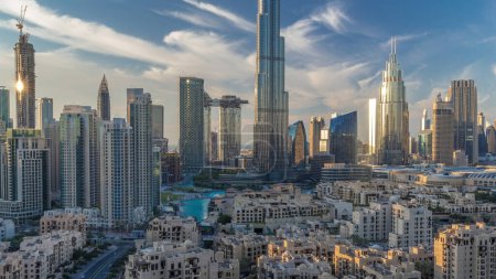 Téléchargez les photos : Dubai Downtown skyline pendant le coucher du soleil avec Burj Khalifa et d'autres tours vue panoramique depuis le sommet à Dubaï, Émirats arabes unis. Bâtiments traditionnels et modernes. Circulation sur la route circulaire et fontaines - en image libre de droit