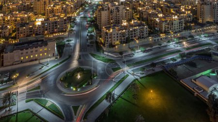 Téléchargez les photos : Vue aérienne d'une route circulaire dans le centre-ville de Dubaï avec des bâtiments traditionnels de style ancien d'au-dessus de la nuit timelapse. Trafic dans la rue. Dubai, Émirats arabes unis
. - en image libre de droit