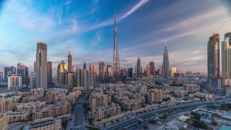 Foto de Dubai Centro skyline con Burj Khalifa y otras torres con largas sombras durante el amanecer vista panorámica desde la cima en Dubai, Emiratos Árabes Unidos. Tráfico en carretera circular y edificios de estilo antiguo - Imagen libre de derechos