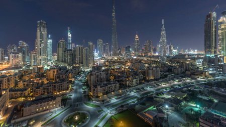 Foto de Dubai Centro skyline noche a día con Burj Khalifa y otros rascacielos vista panorámica desde la parte superior en Dubai, Emiratos Árabes Unidos. Tráfico en la carretera circular. Edificios modernos y tradicionales. - Imagen libre de derechos