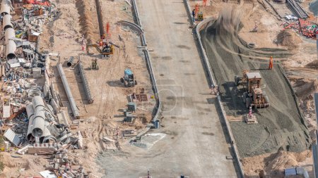 Photo for Excavator, truck and grader working at road construction site in Dubai downtown timelapse. Aerial view from above - Royalty Free Image