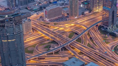 Foto de Vista aérea del intercambio de carreteras en el centro de Dubái noche a día timelapse transición desde el punto de vista. Paisajes urbanos puente de tráfico, logística. Carreteras y carriles Crossroads, Dubai, Emiratos Árabes Unidos - Imagen libre de derechos