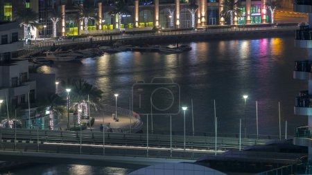 Téléchargez les photos : Marina de Dubaï avec gratte-ciel éclairés et timelapse nocturne aérienne promenade. Tours et bateaux modernes d'en haut avec circulation sur un pont. Émirats arabes unis - en image libre de droit