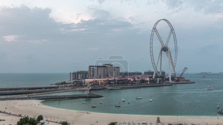 Téléchargez les photos : Bluewaters île et JBR aérien jour à nuit timelapse de transition avec roue ferris, nouvelle zone de marche avec centre commercial et restaurants, nouvellement ouvert lieu de loisirs et de voyage à Dubaï - en image libre de droit