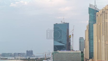 Foto de Vista aérea de la playa y los turistas caminando en JBR con rascacielos en el fondo día a noche timelapse transición en Dubai, Emiratos Árabes Unidos. Frente al mar con muchas actividades y atracciones, tiendas y restaurantes - Imagen libre de derechos