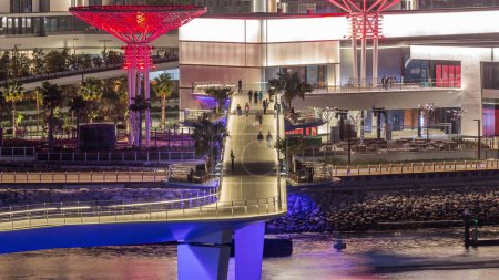 Téléchargez les photos : Passerelle vers Bluewaters île timelapse de nuit aérienne avec les gens sur la nouvelle zone de marche avec des magasins et des restaurants, nouvellement ouvert lieu de loisirs et de voyage à Dubaï - en image libre de droit