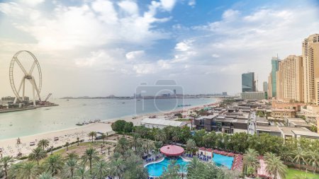 Téléchargez les photos : Vue aérienne de l'horizon de la plage et des touristes marchant dans le timelapse JBR à Dubaï, Émirats Arabes Unis. Des gratte-ciels sur fond. Bord de l'eau avec de nombreuses activités et attractions, boutiques et restaurants - en image libre de droit