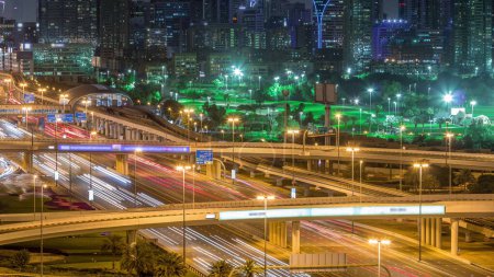 Téléchargez les photos : Dubaï Golf Course avec un paysage urbain des Verts et des districts tecom à l'arrière-plan ciel nuit timelapse. Trafic sur la route Cheikh zayed avec jonction - en image libre de droit