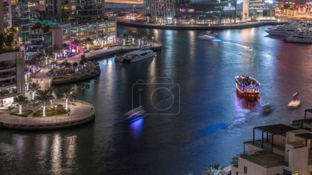 Photo for Waterfront promenade in Dubai Marina aerial night timelapse. Boats and yachts floating on canal. Dubai, United Arab Emirates - Royalty Free Image