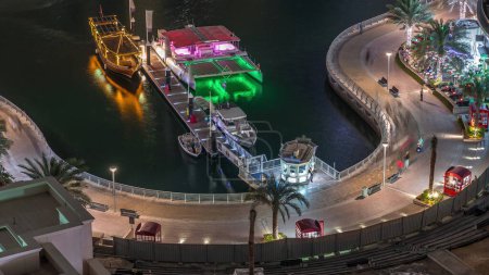 Téléchargez les photos : Promenade au bord de l'eau à Dubai Marina timelapse de nuit aérienne. Bateaux éclairés et yachts flottant sur le canal. Dubai, Émirats arabes unis - en image libre de droit