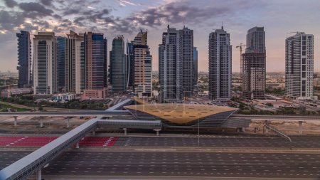 Photo for Aerial view to Sheikh Zayed road during sunrise from Dubai Marina with JLT skyscrapers timelapse, Dubai. Traffic and metro station. Orange cloudy sky. United Arab Emirates - Royalty Free Image