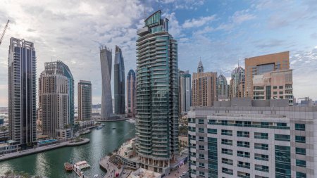 Foto de Vista panorámica aérea de los rascacielos residenciales y de oficinas de Dubai Marina después del atardecer con timelapse de transición día a noche frente al mar. Barcos y yates flotantes - Imagen libre de derechos