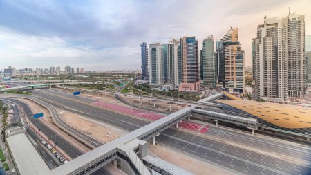 Photo for Aerial top view to Sheikh Zayed road surrounded Dubai Marina and JLT skyscrapers timelapse before sunset, Dubai. Traffic, bridges and metro line. United Arab Emirates - Royalty Free Image