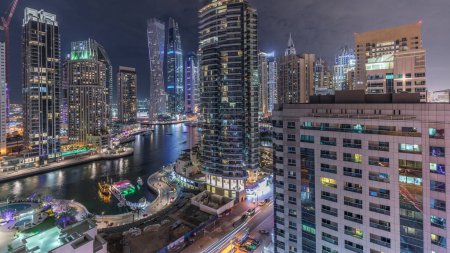 Téléchargez les photos : Vue panoramique aérienne des gratte-ciel résidentiels et de bureau de Dubai Marina avec timelapse nocturne en bord de mer. Bateaux et yachts flottants - en image libre de droit