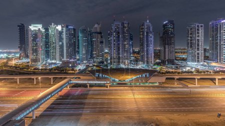 Téléchargez les photos : Vue panoramique aérienne de la route Sheikh Zayed depuis Dubai Marina avec gratte-ciel illuminés par JLT dans la nuit, Dubaï. Trafic, ponts et ligne de métro. Émirats arabes unis - en image libre de droit