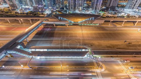 Luftaufnahme der Sheikh Zayed Road in der Nähe des Jachthafens von Dubai und jlt Zeitraffer in der Nacht, Dubai. Verkehr auf der Autobahn, Fußgängerbrücke zwischen U-Bahn und Straßenbahnhaltestelle. Vereinigte Arabische Emirate