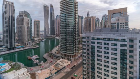 Foto de Vista aérea de los rascacielos residenciales y de oficinas de Dubai Marina con timelapse frente al mar. Barcos flotantes y yates. Cielo nublado por la mañana - Imagen libre de derechos