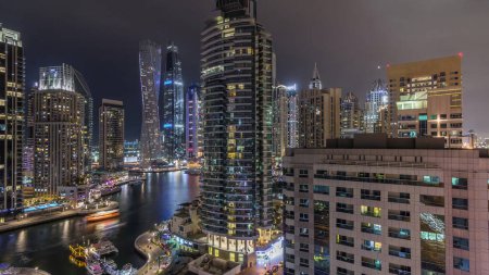 Photo for Aerial view of Dubai Marina residential and office skyscrapers with waterfront night timelapse. Floating boats and yachts - Royalty Free Image