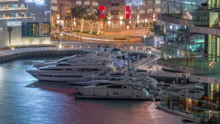 Téléchargez les photos : Promenade au bord de l'eau à Dubai Marina timelapse de nuit aérienne. Bateaux et yachts flottant sur le canal. Dubai, Émirats arabes unis - en image libre de droit