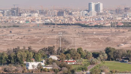 Téléchargez les photos : Vue aérienne sur les villas et les maisons près de Golf Timelapse. Désert et chantier de construction dans le quartier du cercle du village de Jumeirah. Lumière chaude du soir - en image libre de droit