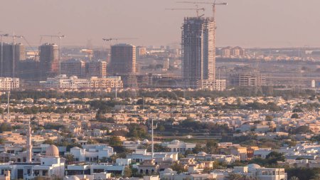 Foto de Vista aérea a villas y casas cerca del campo de golf con timelapse lagos. Sitio de construcción en Jumeirah pueblo círculo distrito. Luz cálida de la noche - Imagen libre de derechos
