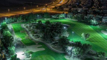 Téléchargez les photos : Vue aérienne des villas et des maisons avec parcours de golf nuit timelapse. Trafic dans les rues. Lacs avec fontaines - en image libre de droit